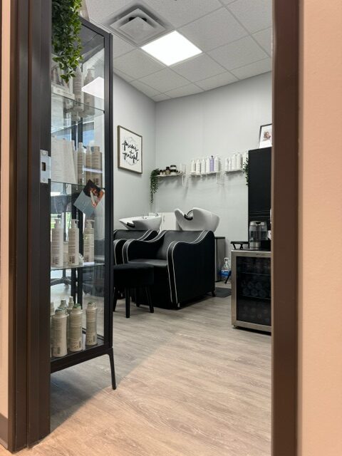 Modern hair salon washing station with products displayed.